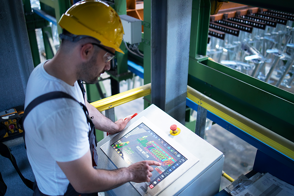 Factory worker monitoring industrial machines production remotely control room