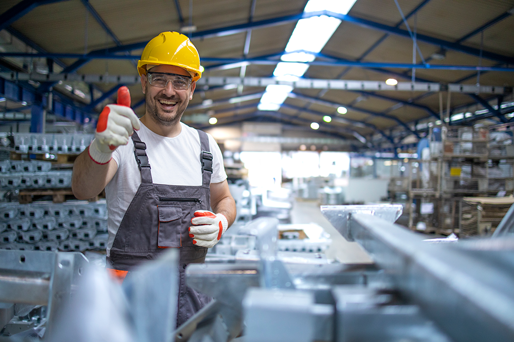 Portrait factory worker protective equipment holding thumbs up production hall